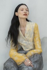 Sticker - A woman with long hair is sitting on a wall wearing a yellow and white outfit. The outfit is made of lace and has a yellow and white pattern. The woman is wearing a ring on her finger