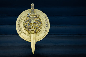 Shield with lion head isolated on dark background. Shield and sword in gold color