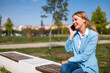 © inesbazdar - Beautiful businesswoman talking on the mobile phone while sitting on the bench outdoor.
