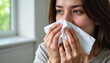© Elfaa - Young woman with a runny nose sneezing into a tissue holding it close to her face indoors