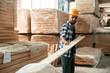 © standret - Taking care of planks, moving them. Industrial worker in wooden warehouse