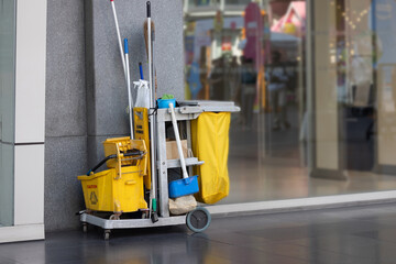 A yellow cleaning cart with a yellow bucket and a blue mop