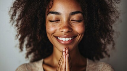 A warm and grateful expression on a smiling woman with hands clasped together. Her joyful appearance radiates positivity and contentment, capturing the essence of gratitude.