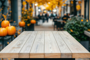Poster - Empty wooden table showing autumn street cafe background with pumpkins and people enjoying their day