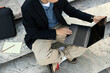 © Seventyfour - Cropped shot of unrecognizable IT programmer using laptop to work keeping fingers on touchpad while writing code sitting on concrete steps outside in street, copy space