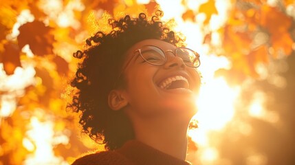 Poster - A joyful young woman with curly hair enjoys the warmth of golden sunlight while surrounded by vibrant fall leaves. Her laughter reflects happiness, creating a cheerful atmosphere in nature.