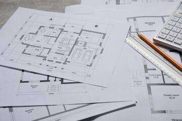 different architectural drawings, calculator, ruler and pencil on gray table, closeup
