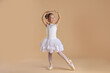 © New Africa - Little ballerina practicing dance moves on beige background