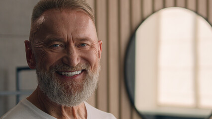 Portrait close up old Caucasian elderly male senior happy smiling toothy mature retired pensioner 60s man smile dental in bathroom indoors home hotel skincare wrinkled face looking at camera carefree