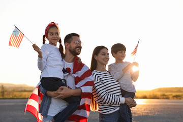 family portrait of happy parents with children waving usa flags outdoors