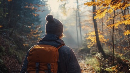 Poster - The hiker walks down a serene trail surrounded by vibrant autumn foliage, basking in the soft glow of early morning sunlight filtering through the trees. The atmosphere is peaceful and invigorating.