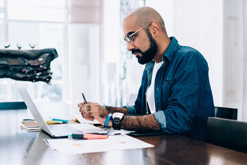 Contemporary bearded man working on laptop