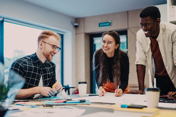 Laughing young colleagues working on project