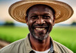 © Selman - Portrait of a middle-aged male farmer smiling, wearing a straw hat in an agricultural setting. The blurred background shows a field, depicting a hardworking and reliable farming professional.