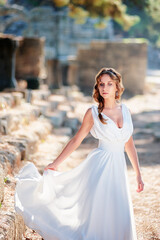 Young beautiful woman wering white dress at antique ruin