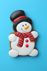 Poster - Tasty Christmas cookie in shape of snowman on light blue background, top view