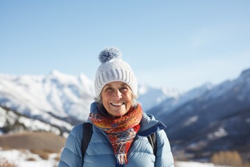 Wall Mural - Portrait of a content woman in her 70s donning a warm wool beanie isolated on pristine snowy mountain