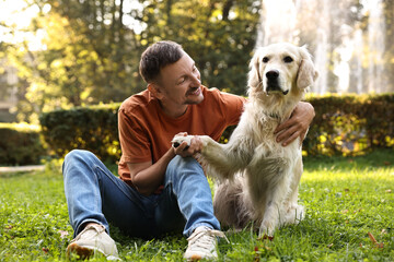 Wall Mural - Smiling man with cute Golden Retriever dog on spring day