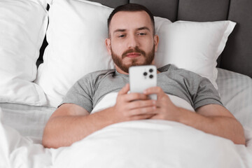 Poster - Handsome man using mobile phone in bed