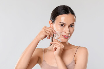 Canvas Print - Beautiful woman peeling off face mask on light grey background