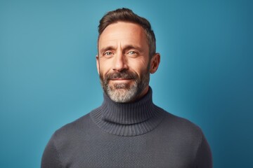 Portrait of a satisfied man in his 40s wearing a classic turtleneck sweater isolated in pastel blue background