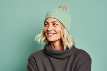 Sticker - Portrait of a merry woman in her 40s donning a warm wool beanie while standing against pastel green background