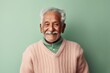 © Markus Schröder - Portrait of a content indian elderly man in his 90s wearing a cozy sweater isolated on pastel green background