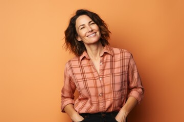 Wall Mural - Portrait of a glad woman in her 40s dressed in a relaxed flannel shirt isolated on pastel orange background