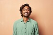 © Markus Schröder - Portrait of a blissful indian man in his 20s sporting a breathable hiking shirt in front of pastel brown background