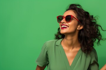 Sticker - Portrait of a cheerful indian woman in her 30s wearing a trendy sunglasses on soft green background