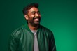 © Markus Schröder - Portrait of a satisfied indian man in his 30s sporting a stylish varsity jacket isolated on soft green background