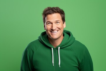 Wall Mural - Portrait of a happy man in his 40s wearing a zip-up fleece hoodie on soft green background