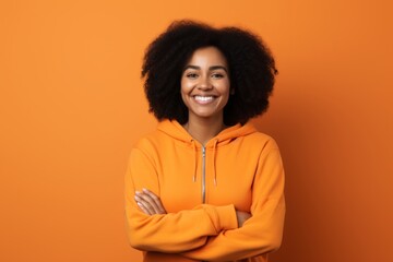 Poster - Portrait of a satisfied afro-american woman in her 30s wearing a zip-up fleece hoodie in front of soft orange background