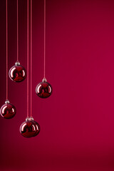 Wall Mural - Minimalistic  burgundy Christmas background with hanging ornaments. Christmas decorations featuring crimson and wine-colored ornaments on a deep red background with copy space.