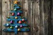 © Rangga Bimantara - A decorative wooden Christmas tree made from blue pallets, adorned with colorful ornaments and a star, set against a rustic wooden background.