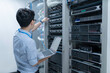 © reewungjunerr - Computer engineer is setting up network in server room,Systems Maintenance Technician,Male engineer working in server room at modern data center