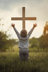 Praising the lord concept. Back view of a young boy with his arms raised to the sky in thankfulness and prayer. Themes such as Rebirth, Intervene, Guidance