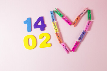 Whit fourteen days of February, and made a heart of colorful clamps on the pink background. Valentine's day concept.