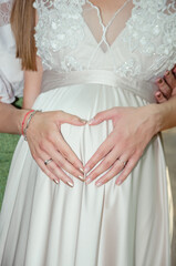 Sisters hands making heart on pregnant bride, love, family