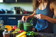 © tynza - A fitness enthusiast preparing a spirulina shake with protein powder and fruits, with the kitchen in the background.
