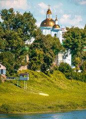 A white building with a striking gold dome and cross on top