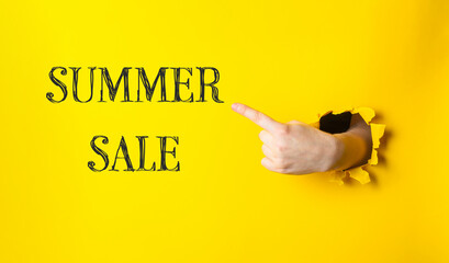 A hand pointing to a yellow sign that says Summer Sale