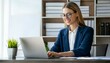 © l1gend - Young happy professional business woman worker employee sitting at desk working on laptop in corporate office. Smiling female student using computer technology learning online, doing web research.