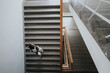 © qunica.com - A student with a backpack ascends a wide staircase in a well-lit, modern building, symbolizing education and progress. The architectural lines create a striking visual perspective.