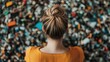 © Dulemegapixel - A woman wearing an orange dress with her hair in a bun gazes at a colorful pile of trash, highlighting themes of consumerism and environmental concerns.