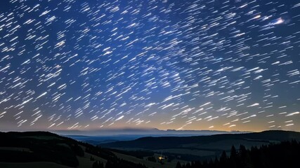 Aufkleber - Long exposure captures the mesmerizing movement of stars, creating bright streaks across the twilight sky above a peaceful mountain landscape