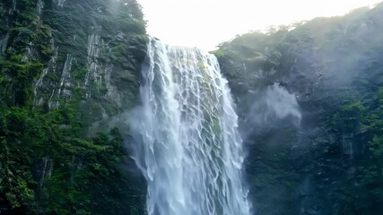 Poster - Cascading water down steep cliff, surrounded by lush green plants with rising mist. Graceful waterfall flows, creating scenic, refreshing scene in rainforest jungle