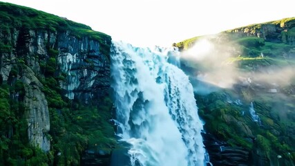 Aufkleber - Powerful white waterfall cascades down a mossy cliff, creating mist in soft morning light, flowing over rocks surrounded by lush green moss