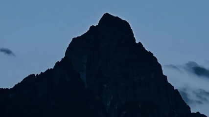Poster - Tall mountain peak stands proudly against the twilight sky, with low hanging clouds adding to the dramatic atmosphere