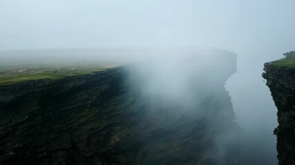 Wall Mural - thick fog envelops rugged cliff, hiding ocean view on moody day. green grass adds to atmospheric sce